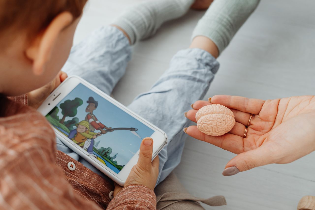 A child watches a cartoon on a smartphone indoors.